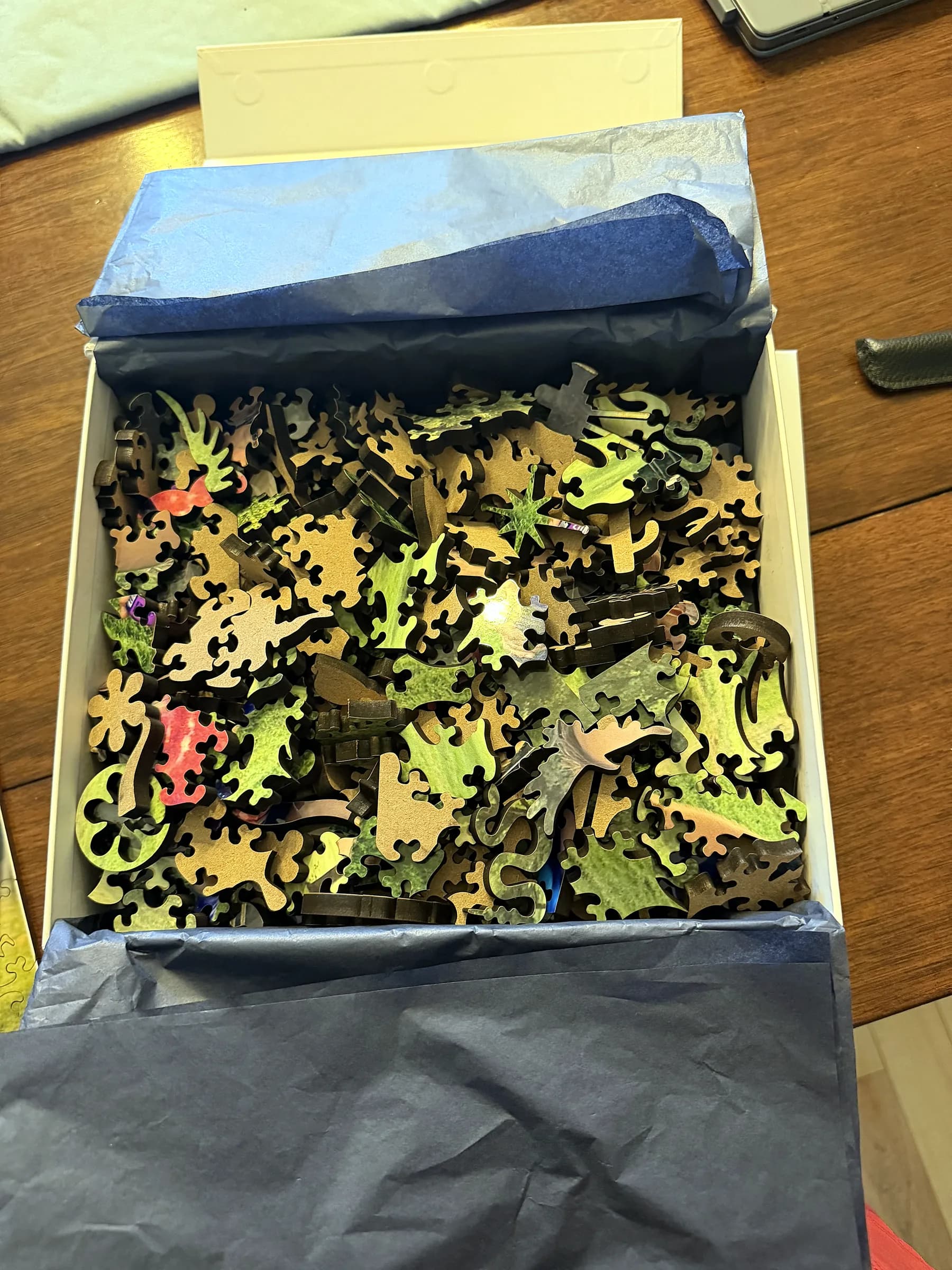 An opened Whittled box with tissue and wooden puzzle pieces inside